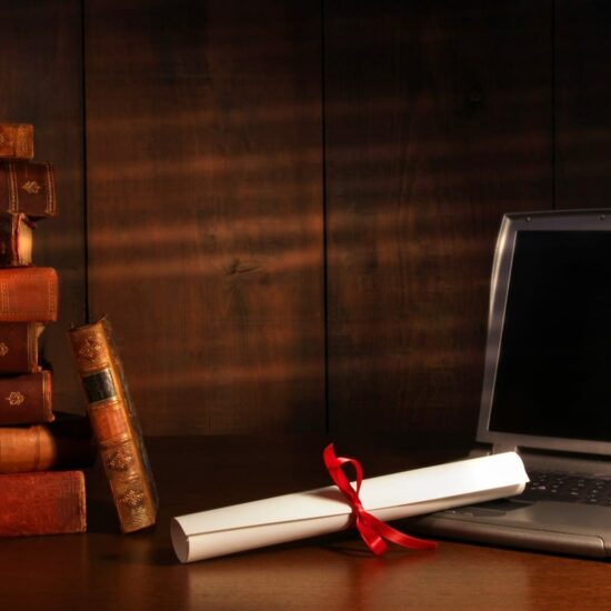 Antique books, diploma with laptop on desk