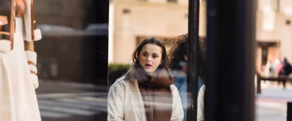 amazed woman standing near glass showcase of store