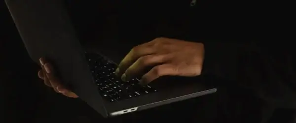 crop unrecognizable man using laptop in darkness