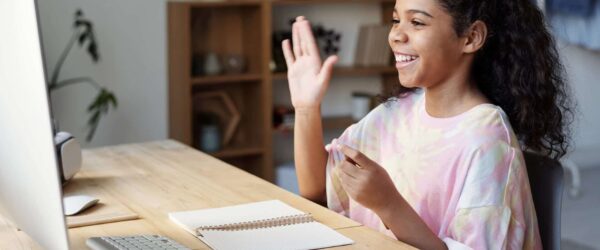 woman in pink shirt sitting by the table while smiling