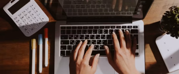 person using macbook pro on brown wooden table