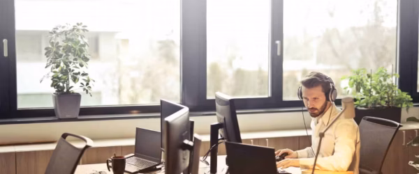 man with headphones facing computer monitor