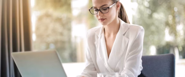 concentrated female entrepreneur typing on laptop in workplace