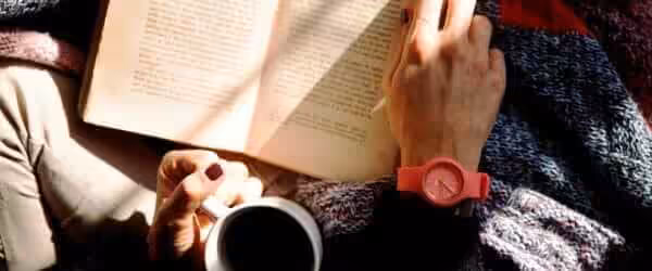 person reading book and holding coffee