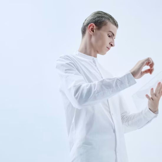 a low angle shot of a man in white long sleeves holding a clear glass