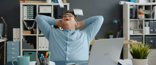 lots of money falling on handsome guy in office sitting at desk alone enjoying wealth.