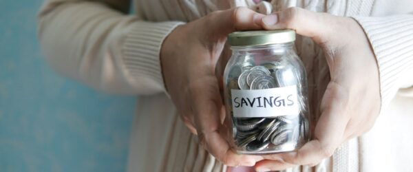 Woman holding a savings jar — building better money habits to stop the debt cycle