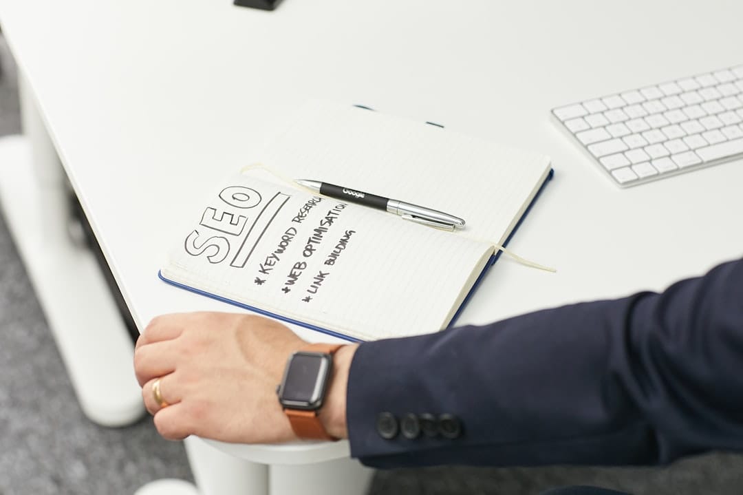 Notebook with an SEO strategy outline covering keyword research, optimisation and link building