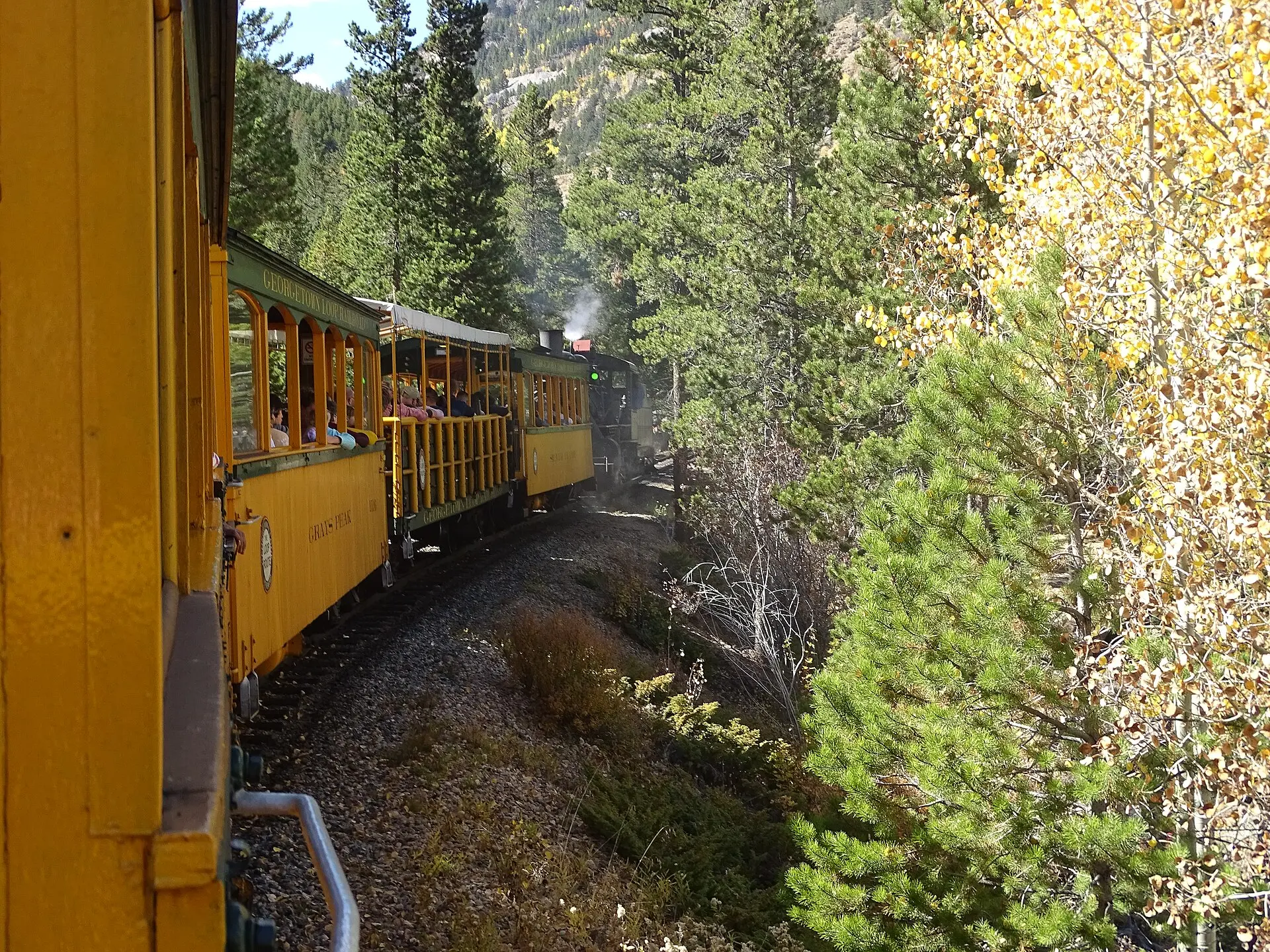 Steam locomotive hauling open-air passenger cars on the Georgetown Loop Railroad through the Colorado mountains