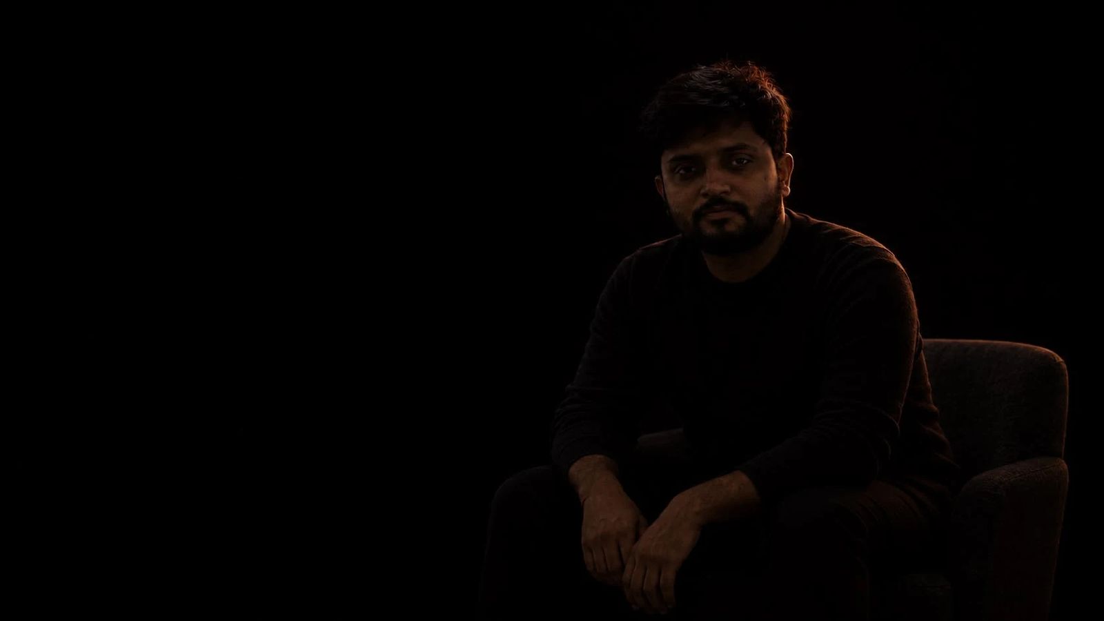 Gaurav Tiwari seated in an armchair in a dark studio