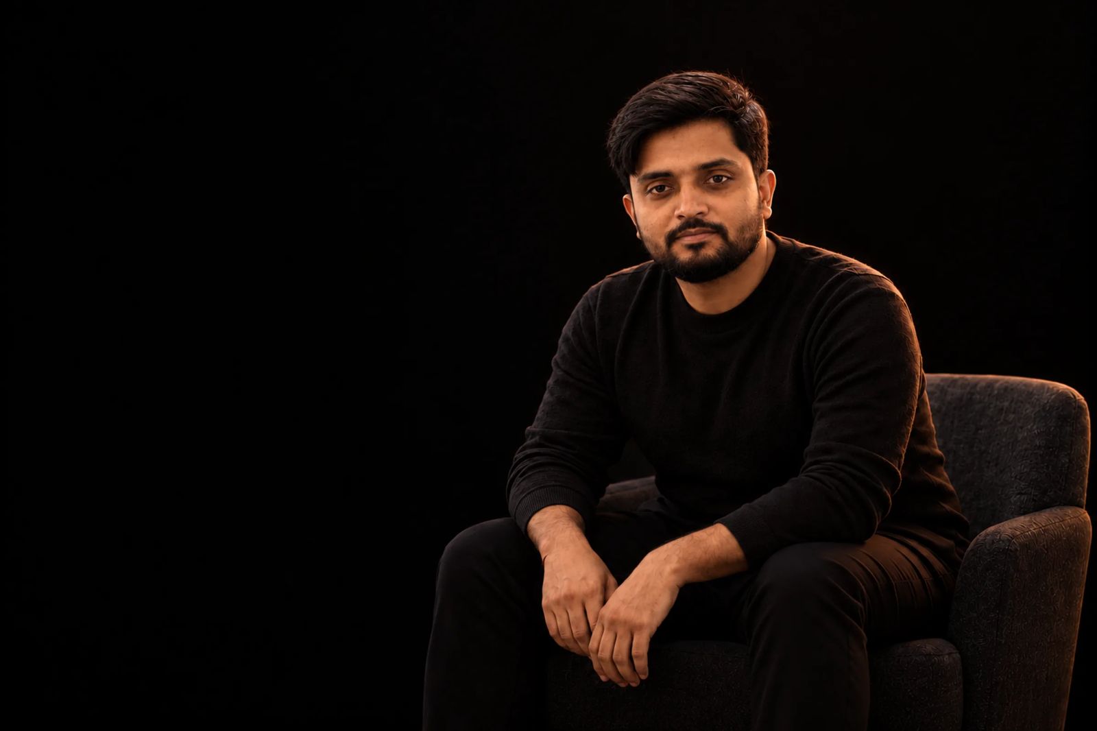 Gaurav Tiwari seated in an armchair in a dark studio