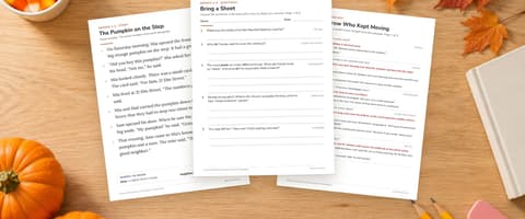Three printed Halloween reading comprehension worksheets, a story page, a question sheet and an answer key, on a wooden desk with pumpkins, autumn leaves and candy corn